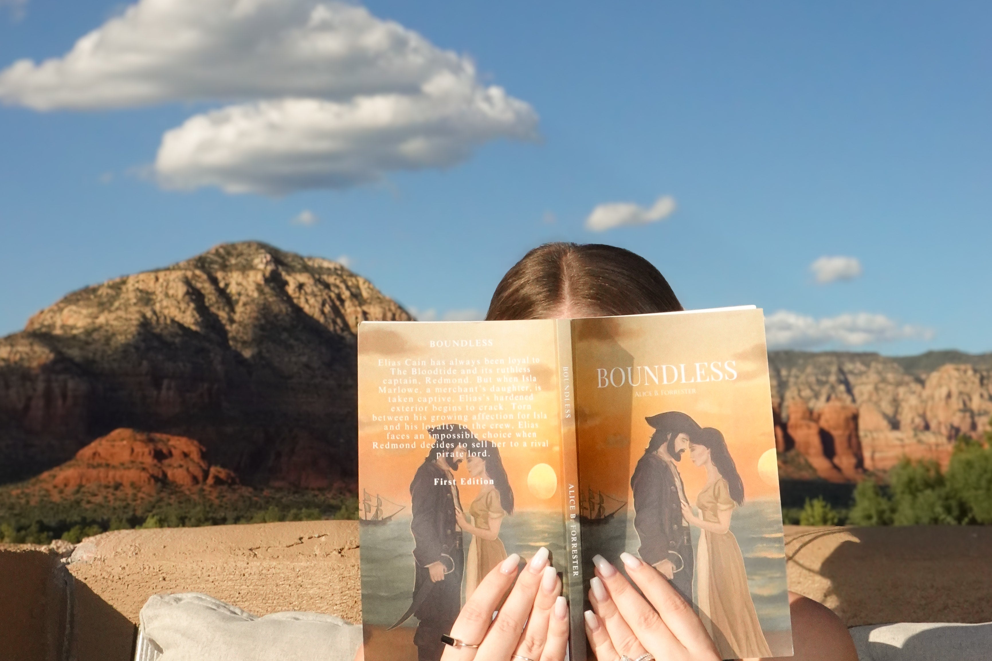 Person reading a book titled 'Boundless' with desert landscape in the background